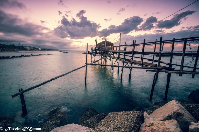 Fotografia al tramonto sul mare con ponte di legno