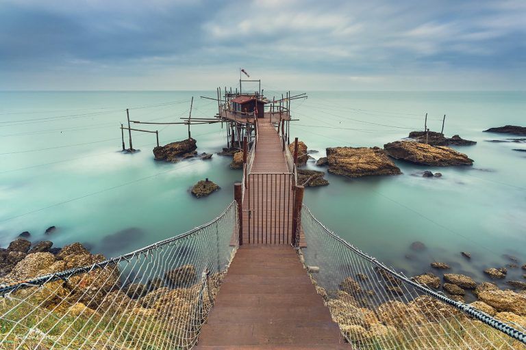 Paesaggio marino: passerella e mare setoso nella lunga esposizione