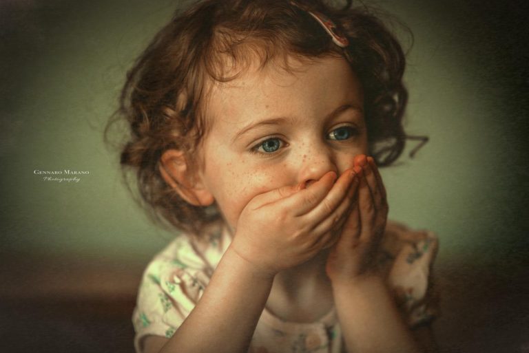 Ritratto di bambina: luce morbida, lentiggini e gesto sospeso