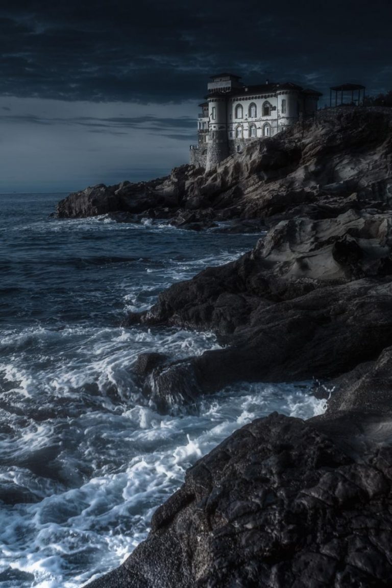 Castello sul mare: rocce e onde in una scena crepuscolare