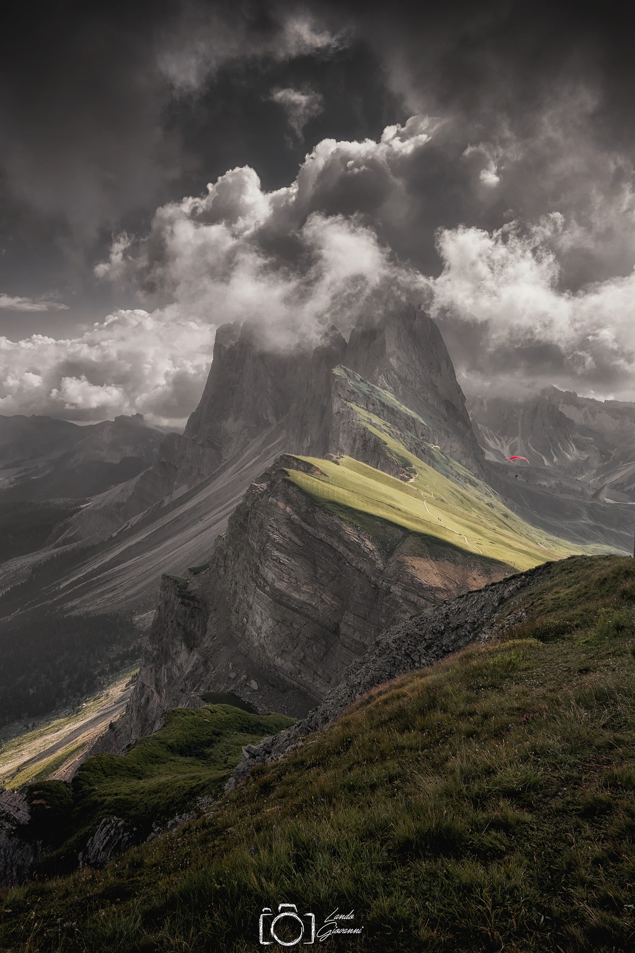 Massa di nuvole, vetta dominante e verde in primo piano: paesaggio d’alta quota