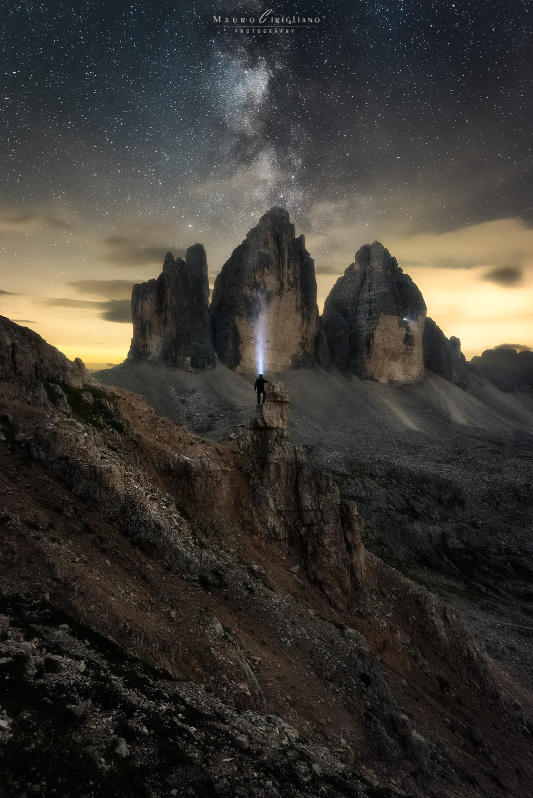 Traccia di luce verso l’alto: figura alpinistica tra guglie e cielo stellato